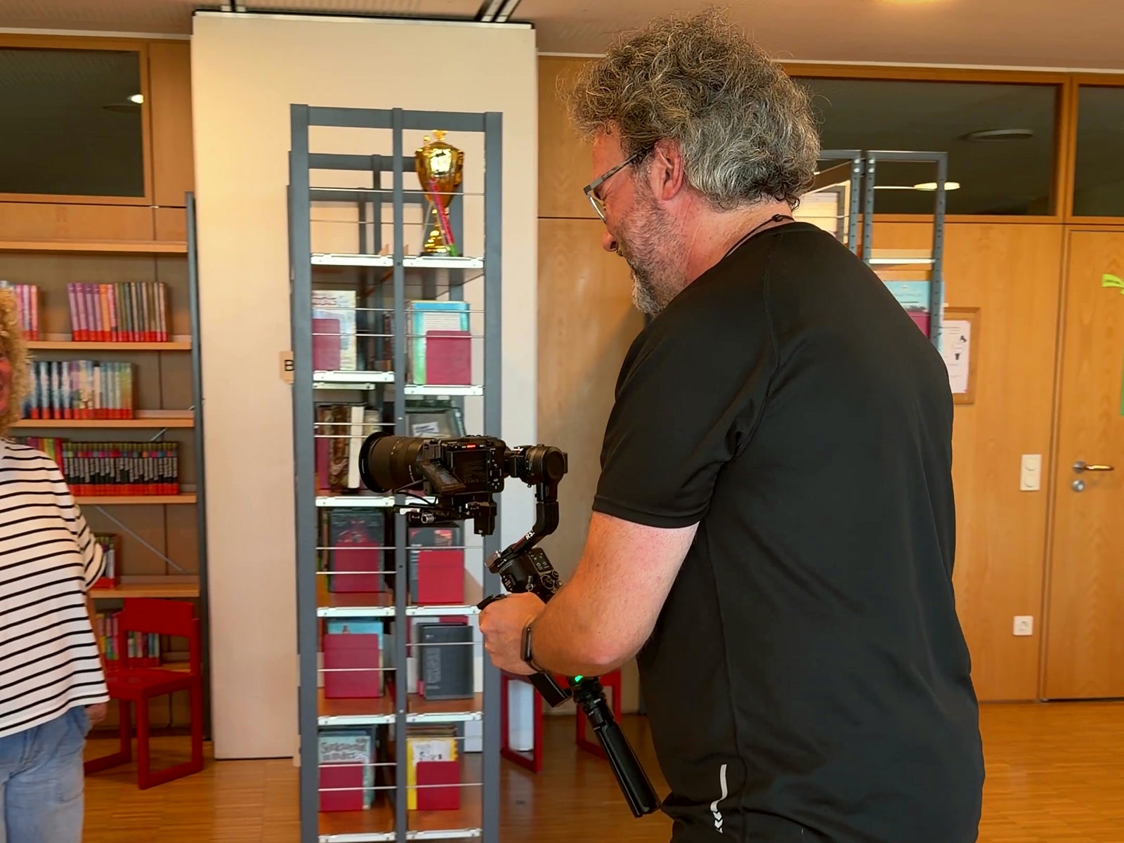 Arne Kocher dreht mit dem Gimbal zwischen den Bücherregalen