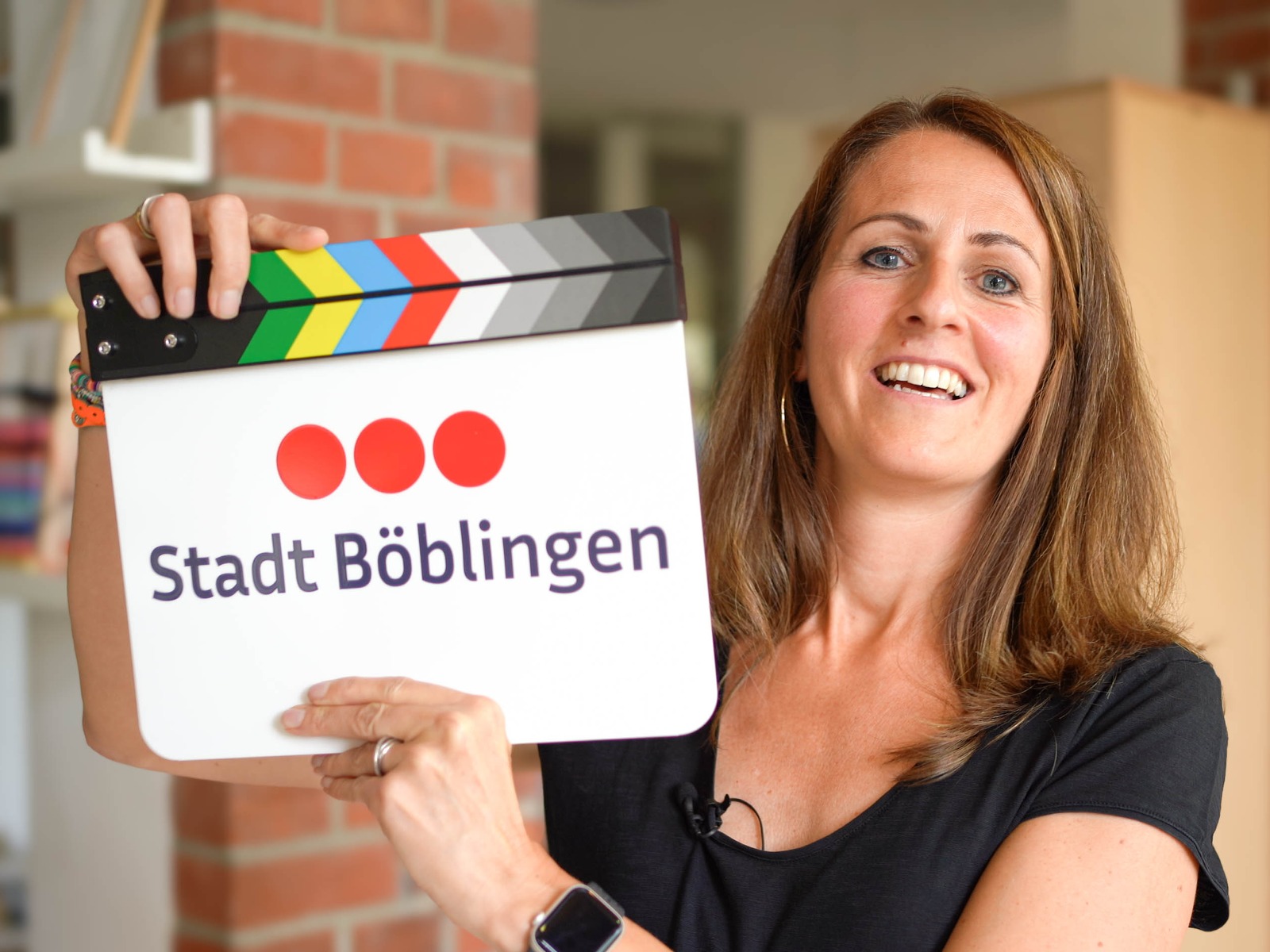 Erzieherin der Stadt Böblingen lacht mit der Filmklappe im Familienzentrum, Dreh für die Berufswelt Pädagogik