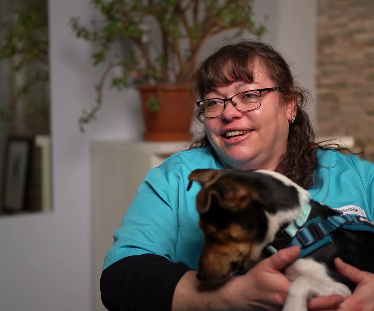 Mitarbeiterin von Wandtke Dental lacht mit Bürohund Freddy, Recruiting-Video Beispiel aus dem Handwerk